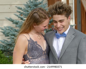 A Cute High School Couple, Dressed Up, Posing For The Camera Before Their Homecoming Dance.