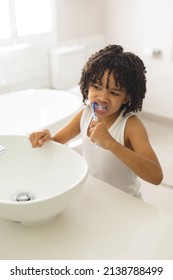 Cute Hispanic Boy With Curly Black Hair Brushing Teeth In Bathroom At Home. Unaltered, Childhood, Hygiene And Routine Concept.