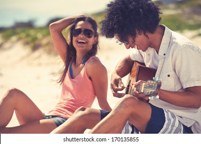 Cute hispanic couple playing guitar serenading on beach in love and embrace - Powered by Shutterstock