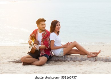 Cute Hispanic Couple Playing Guitar serenading on beach in love and embrace