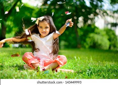 Cute Hispanic Girl Throwing Confetti At Park