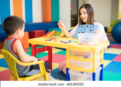 Cute Hispanic language therapist working with a kid in a special needs school