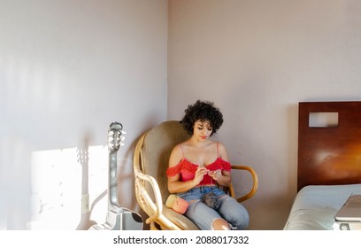 Cute Hispanic Millennial Woman, Knitting Sitting On Her Bedroom Couch