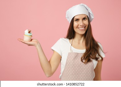 Cute housewife chef cook confectioner baker in white t-shirt, toque chefs hat cooking hold sweet isolated on pink pastel background in studio. Cupcake making process. Mock up copy space food concept