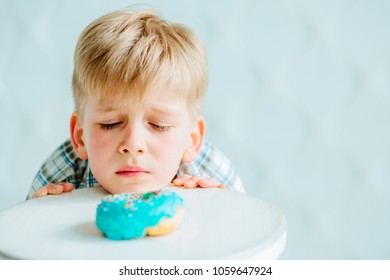 Cute hungry baby boy looking on sweet donut
