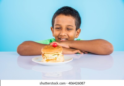 cute indian boy eating burger, small asian boy and burger, over blue background 