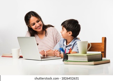 Cute Indian Boy With Mother Doing Homework At Home Using Laptop And Books - Online Schooling Concept