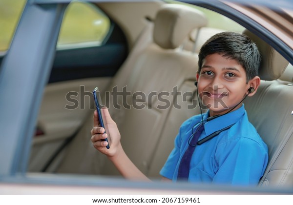 Cute\
indian child sitting in car and using\
smartphone