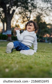 Cute Indian Little Child Face Closeup On Green Grass In Summertime. Funny Little Kid Portrait With Mobile Phone, Smartphone On Nature. Happy Childhood.