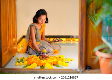 Cute Indian Little Girl Making Decoration With Flower And Oil Lamp For Diwali Festival At Home.