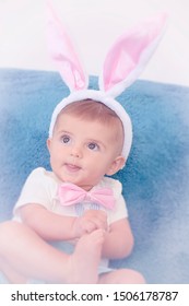 Cute Infant Baby Boy Dressed Up In Easter Bunny Rabbit Holding Foot And Poking His Tongue Out