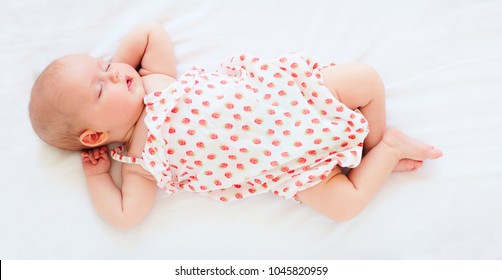 Cute Infant Baby Girl In Bodysuit Sleeping In Bed. Top View