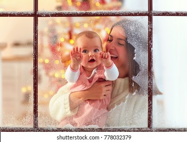 Cute Infant Baby Girl In Mother Hand Looking Through The Window, Family Winter Holidays