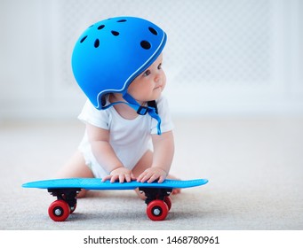 cute infant baby girl in protective helmet outfit ready to ride skateboard, extreme sport concept