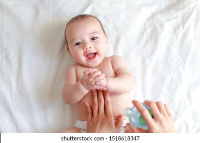 Cute Infant Boy Massaging At Home. Mother Applying Oil On Her Baby Makes Belly Massage. Mixed Race Asian-German Kid