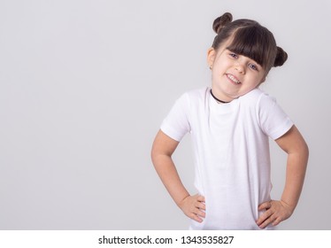 Cute Kid 5 Years Old Wearing White T-shirt Shrugging Shoulders And Looking At Camera. Isolated On White Background. 