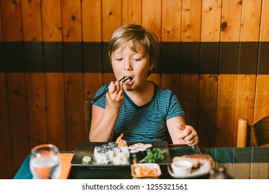 Cute Kid Boy Eating Sushi In Asian Restaurant