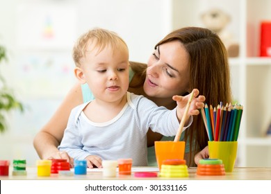 Cute Kid Boy Painting With Paintbrush At Home Or Day Care Center