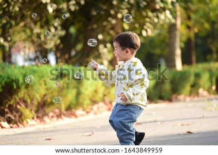 A cute kid chasing bubbles and playing