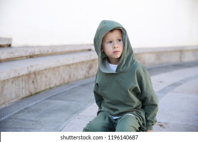 Cute Kid Or Child In The Hoodie Sitting On A Ball In The Park 