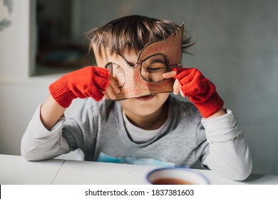 Cute Kid In Disguise With DIY  Cardboard Superhero Mask At Home. Boy With Creative Halloween Costume Or Festive Apparel For Children Theater. Playful Spirit Concept. Home Celebration With Family.