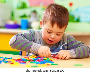 cute kid with down's syndrome playing in kindergarten - Shutterstock ID 528036100