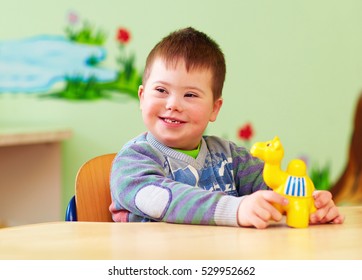 Cute Kid With Down's Syndrome Playing In Kindergarten