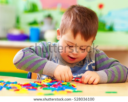 cute kid with down's syndrome playing in kindergarten