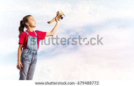 Cute kid girl in overalss with retro plane model in hand