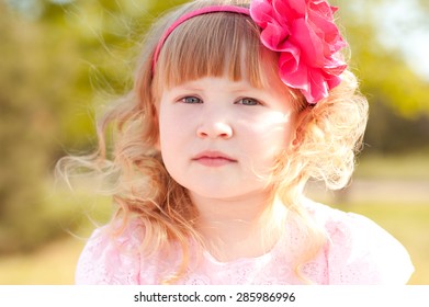 Cute Kid Girl Posing Outdoors. Wearing Hairband With Pink Flower. Childhood. 