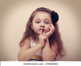 Cute kid girl showing silence sign the finger near lips. Vintage closeup portrait