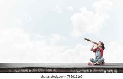 Cute Kid Girl Sitting On House Roof And Looking In Spyglass