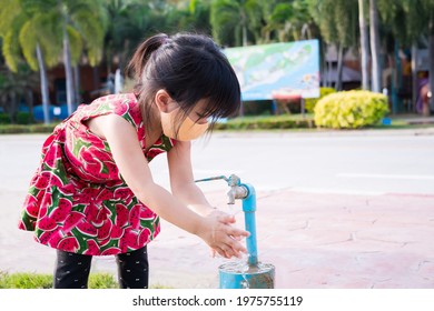 Cute Kid Girl Wearing Cloth Face Mask Is Washing Her Hands With Clean Water From Faucet In Public Area After She Does Her Activity. Child 4 Years Old. Prevent Spread Of Coronavirus (COVID-19) Disease.