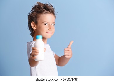 Cute Kid Holding Plastic Bottle Of Milk On Blue Background