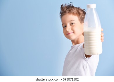 Cute Kid Holding Plastic Bottle Of Milk On Blue Background