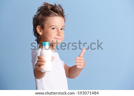 Cute kid holding plastic bottle of milk on blue background