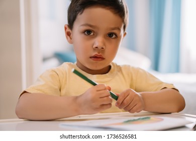 cute kid looking at camera while holding felt-tip pen