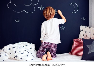 Cute Kid In Pajamas Painting Chalkboard Wall In His Bedroom.