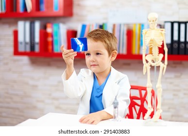 cute kid playing a doctor, looking at x-ray image of leg