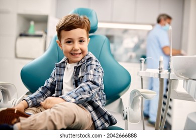 Cute kid sitting in dentist's chair and looking at camera. 
