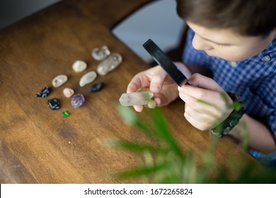 A cute kid studying semi precious stones on a rustic table background. Montessori and Waldorf school concept. Autism and OCD concept.