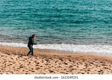 Cute Kid Throwing Rocks At The Ocean