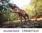 Cute kid walking in dinosaur park. Tourist attraction for children. Happy child having fun at dino park. Summer camp, vacation and weekend day.