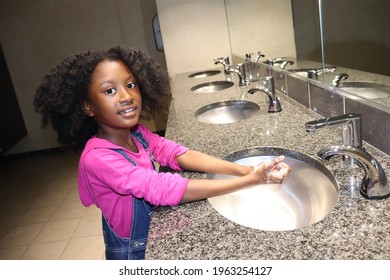 Cute Kid Washing Hands In Public Bathroom Sink