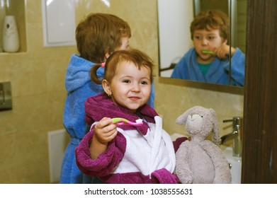 Cute Kids In Bathrobes In The Bathroom Brushing Their Teeth