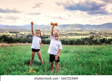 Cute Kids, Boy And Girl, Doing The Morning Exercises With Dumbbells On The Top Of The Mountains In Summer Nature, Morning Exercises, Sport And Healthy Lifestyle, Outside