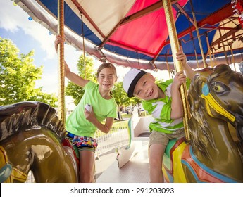 Cute Kids Having Fun Riding On A Colorful Carnival Carousel