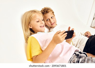 Cute Kids Lie Next To The Phone In Their Hands Playing