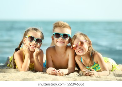 Cute Kids Lying On Beach Sand