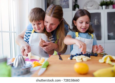 Cute Kids With Mother Preparing A Healthy Fruit Snack In Kitchen 